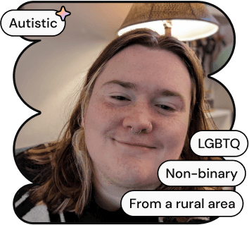 A photo of Jacob, one of ND Connect's co-founders. They are a white non-binary person with long brown hair, smiling at the camera. He is wearing a sweater with pumpkins and cartoon ghosts on it.